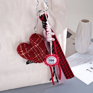 Chic red heart plush charm with houndstooth ribbon and poker chip on white leather bag