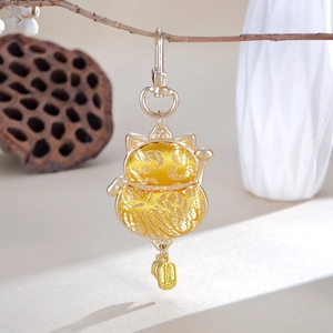 Detail of handmade lucky cat embroidery pendant with gold fortune charm and wave pattern