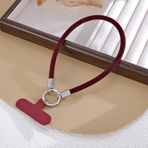Close-up of burgundy braided leather phone wrist strap with silver metal clasp and pad