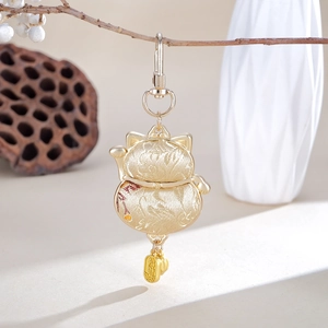 Close-up of golden embroidered Maneki-Neko pendant with intricate silk weaving details
