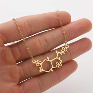 Detailopname van een gouden ketting met chemische molecuulstructuur en bloem- en bladhangers
