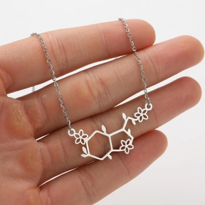 Zilveren ketting met chemische molecuulstructuur en klein bloemetje op de hand