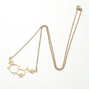 Detail van de gouden bloemmolecuul hanger aan een fijne roestvrijstalen ketting