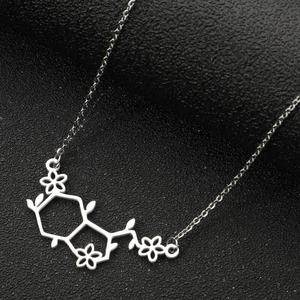 Zilveren ketting met chemisch molecuul en bloemenhanger op zwart getextureerde achtergrond