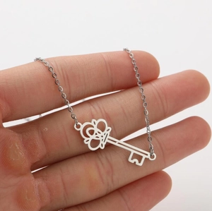 Detalle de un colgante de llave de plata con corona en una cadena de eslabones finos