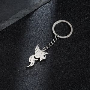 Detailed close-up of a silver hollow bird pendant keychain on a dark stone background