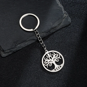 Detailed macro view of a silver stainless steel Tree of Life keychain on a slate stone