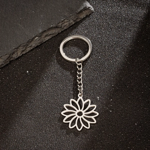 Detail of silver hollow sunflower keychain on a textured black industrial background