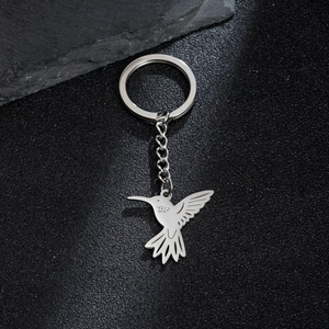 Macro shot of silver hummingbird keychain charm on black stone texture background