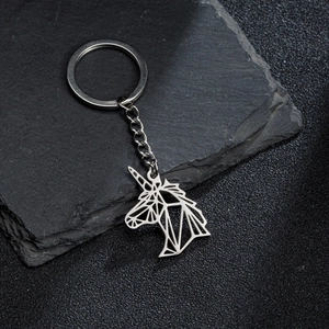 Detailed shot of a silver geometric origami unicorn keychain on a dark textured rock