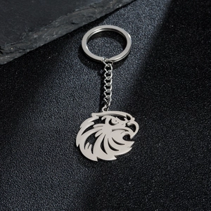 Detailed macro view of an eagle head shaped stainless steel keychain on black leather texture