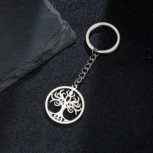 Detailed view of stainless steel tree of life keychain pendant on a dark stone surface