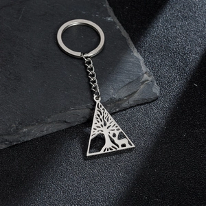 Detailed close-up of hollowed stainless steel tree of life and deer charm on a keychain