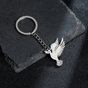 Detailed view of a silver dove pendant keychain with olive branch on a stone texture