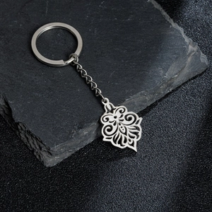 Detail of stainless steel keychain with hollow floral pattern on black stone surface
