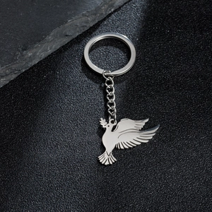 Detailed view of flying peace dove keychain with olive branch on textured dark background