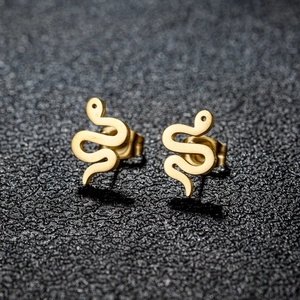 Macro shot of gold snake stud earrings in minimalist S-curve design with glossy metal finish