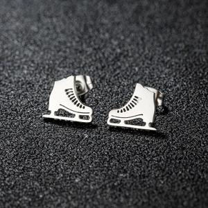 Boucles d'oreilles patins à glace en acier inoxydable poli sur fond texturé sombre