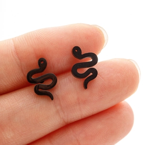 Macro shot of minimalist black snake stud earrings shown on fingers for size