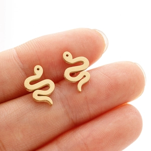 Close-up of minimalist golden stainless steel snake stud earrings held between fingers