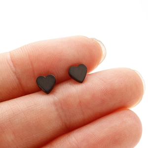 Minimalist black heart-shaped stainless steel stud earrings shown for scale