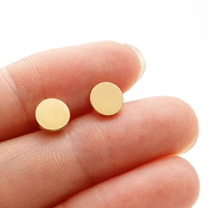 Detailed close-up showing gold circular stud earrings size held by hand on white background