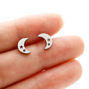 Macro shot of star and moon stainless steel stud earrings held between fingers