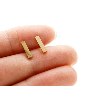Vue macro de boucles d'oreilles rectangulaires dorées montrant la taille précise