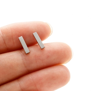 Vue détaillée montrant la taille des boucles d'oreilles rectangulaires en acier brossé