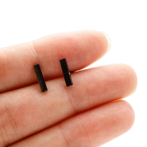 Gros plan de boucles d'oreilles rectangulaires minimalistes en acier inoxydable noir en main