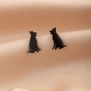 Macro detail of cute black German Shepherd silhouette stud earrings on silk fabric