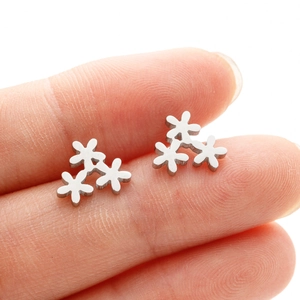 Macro shot of silver daisy flower stud earrings showing fine floral details and size scale