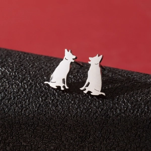 Macro shot of silver puppy silhouette stud earrings on a textured black and red background