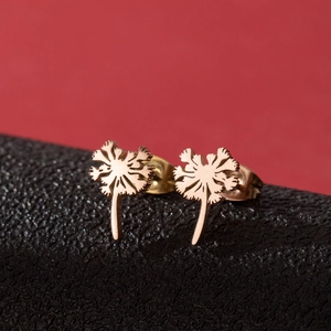 Macro shot of rose gold dandelion stud earrings on black leather with red background