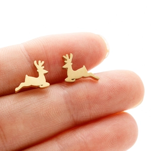 Macro shot of minimalist gold reindeer stud earrings held by hand for scale