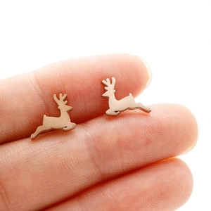 Close-up of mini stainless steel reindeer stud earrings on a fingertip for size reference