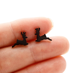 Macro shot of minimalist black reindeer stud earrings held on a fingertip for scale