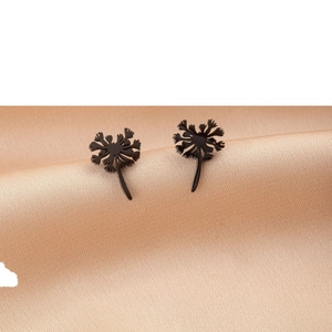 Minimalist black dandelion stud earrings on elegant champagne silk fabric background