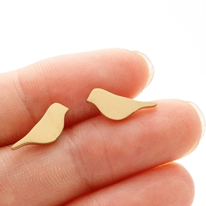 Macro shot of gold bird-shaped stainless steel earrings held on fingertips
