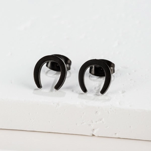 Gros plan de boucles d'oreilles fer à cheval noires en forme de U sur socle en pierre blanche