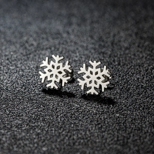 Pendientes de botón minimalistas con forma de copo de nieve sobre fondo oscuro texturizado
