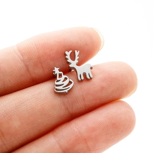 Macro detail of asymmetric stainless steel reindeer and Christmas tree stud earrings