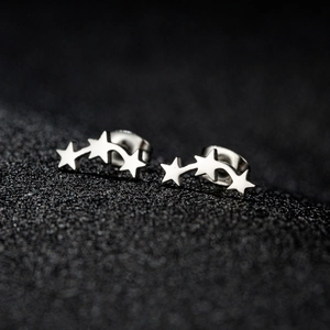 Vue macro de boucles d'oreilles étoiles argentées avec design météore sur fond noir