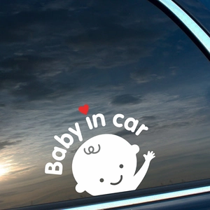 Baby in car sticker with cartoon infant and red heart on a car window at sunset
