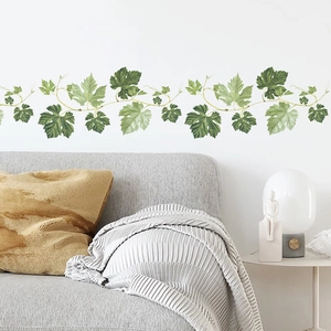 Green leaf vine wall stickers for living room decor above a modern grey sofa