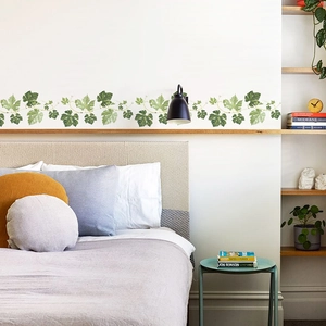 Macro detail of lush green leaf wall stickers applied as a border in a cozy bedroom setting