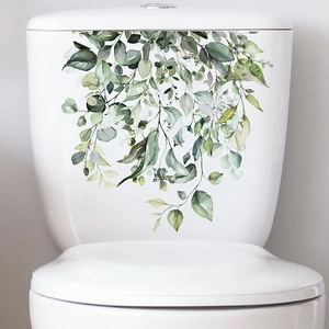 Detail view of self-adhesive green plant leaf stickers applied to a white toilet tank surface