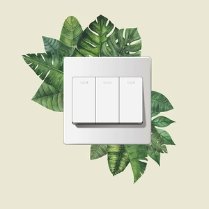Minimalistischer weißer 3-fach Wandschalter umgeben von dekorativen Tropenblättern