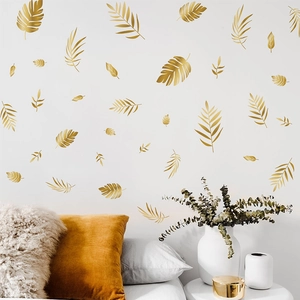 Golden metal leaf wall decals set featuring palm and pinnate leaf shapes for home decoration
