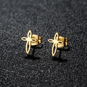 Vue macro de boucles d'oreilles croix dorées avec découpes géométriques et éclat poli